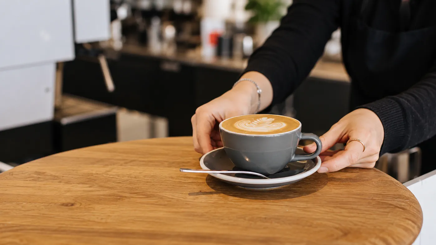 A fresh cup of coffee being served across the counter