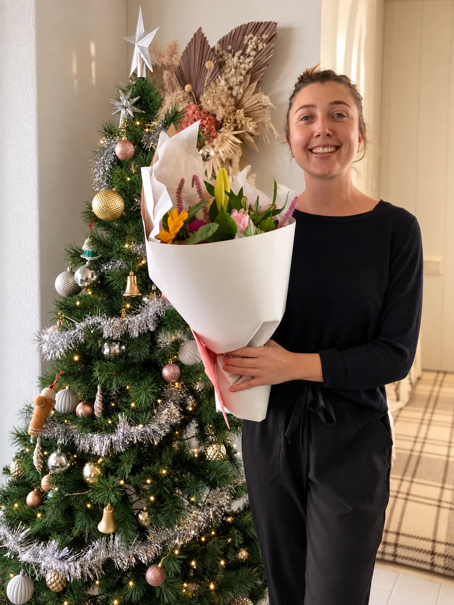 Person holding a bouquet beside a decorated Christmas tree