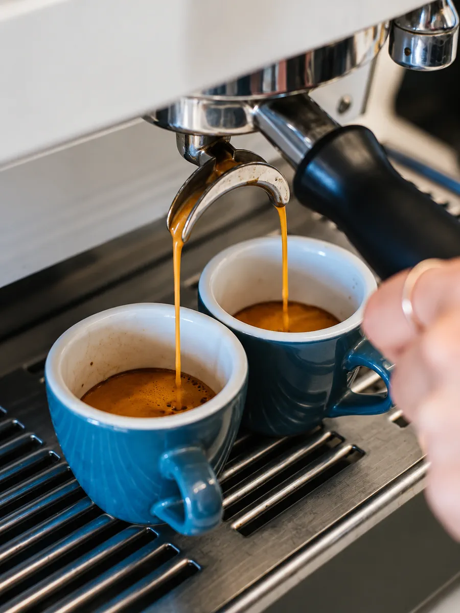 Espresso pouring into blue coffee cups